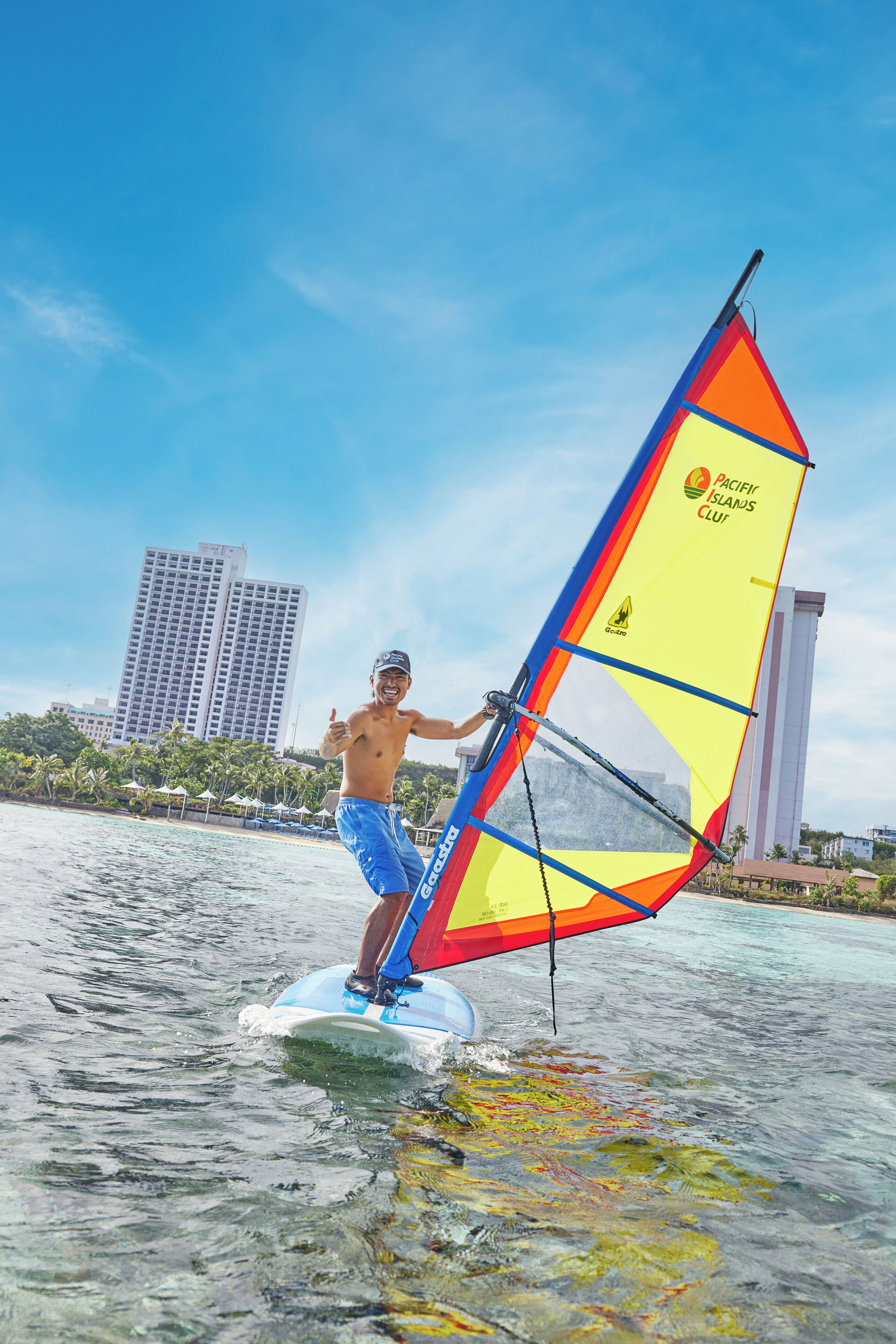 A person windsurfing on a clear day with a cityscape in the background.
