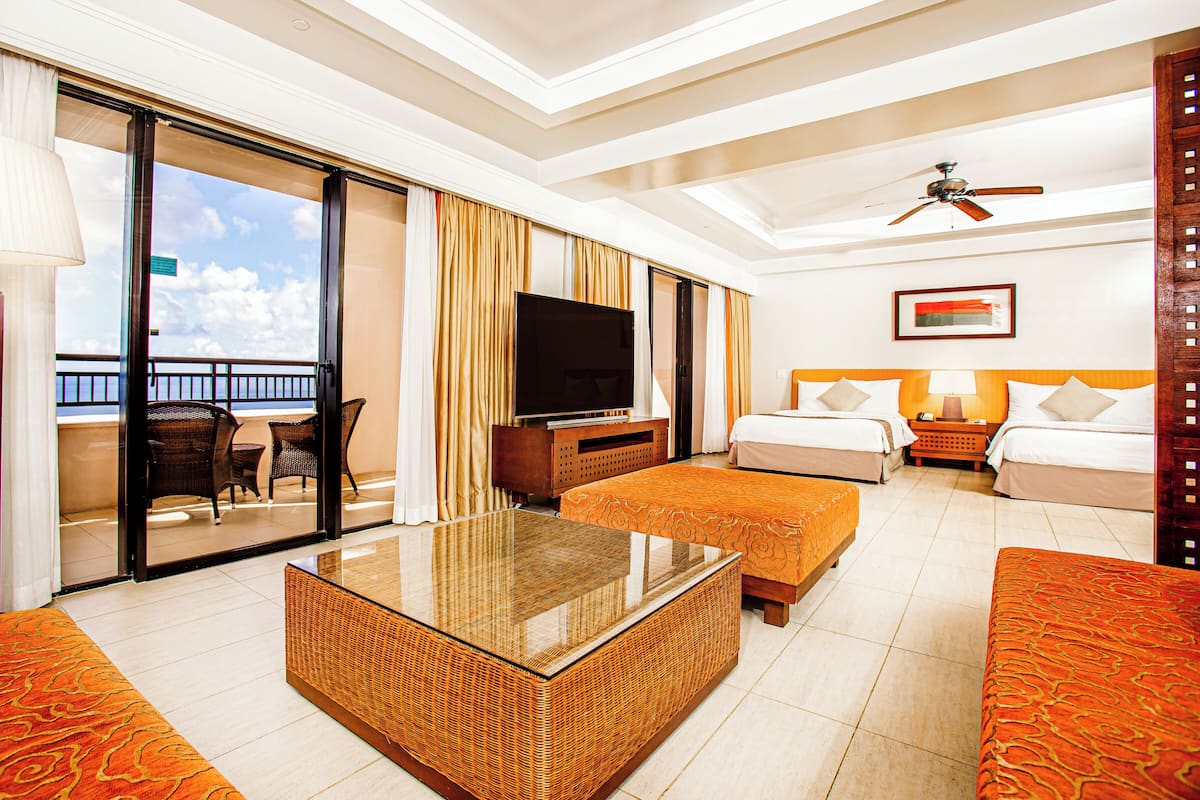 A hotel room with a balcony, a television, a bed, a sofa, and a coffee table.