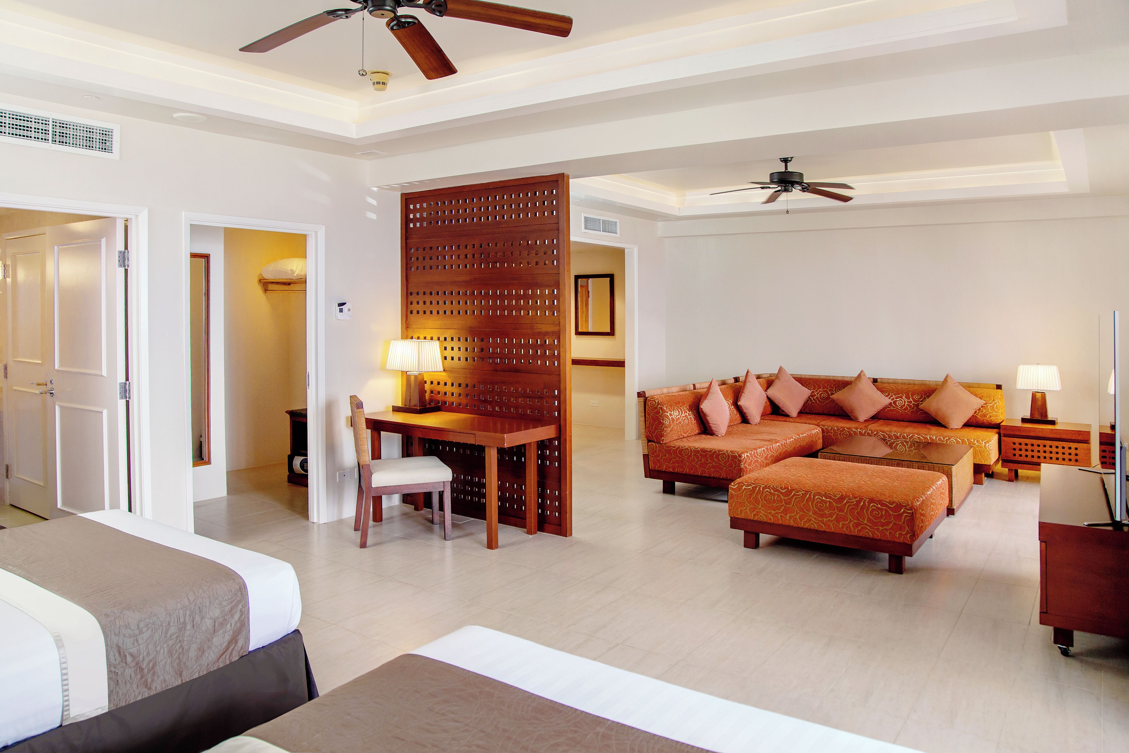 A hotel room with a bed, a sofa, a dining table with chairs, and a partition wall.