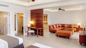 A hotel room with a bed, a sofa, a dining table with chairs, and a partition wall.