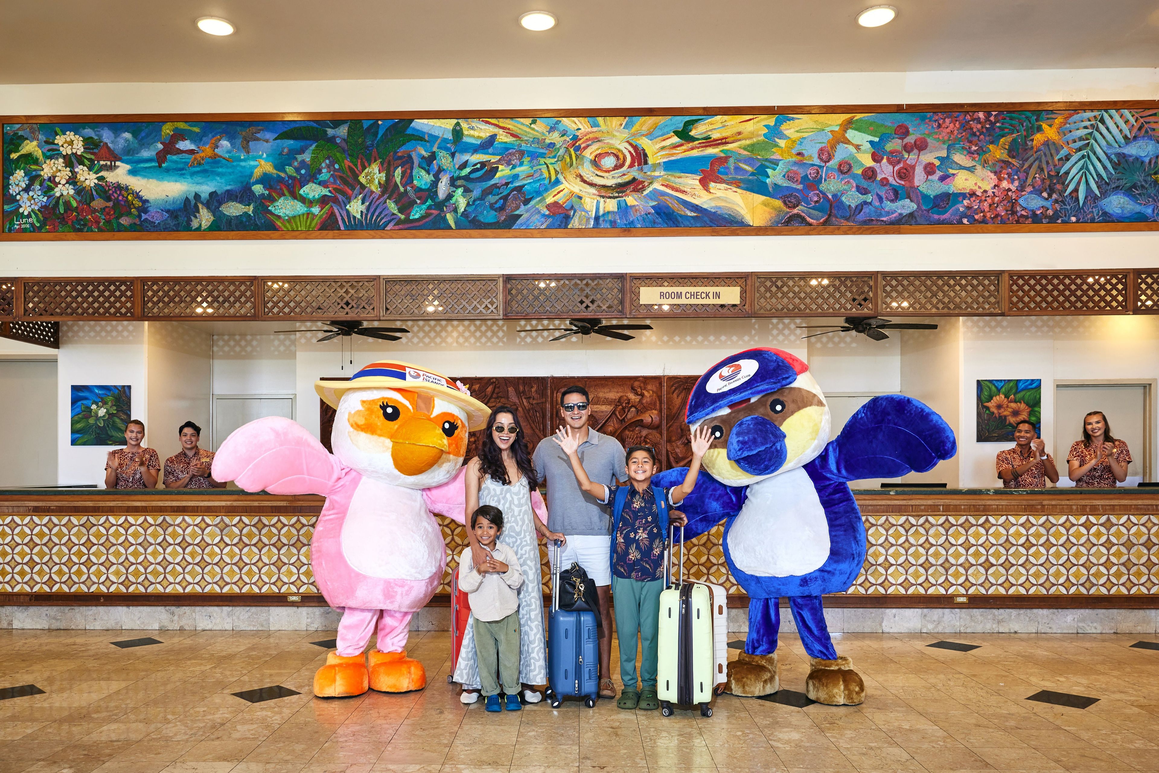 A reception area with a large mural, a 'Room Check In' sign, and a reception desk with staff.