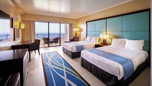 A hotel room with two beds, a desk, and a balcony with a view.