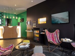 Um lobby moderno com balcão de recepção, área de estar e geladeira com bebidas.