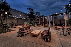 An outdoor seating area with sofas, tables, and string lights.