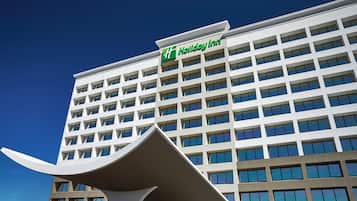 A multi-story building with a prominent 'Holiday Inn' sign, featuring a modern architectural design with a flat facade and numerous windows.