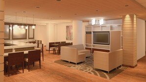 A modern hotel lobby with a dining area, seating, and a TV. - Holiday Inn Alexandria at Carlyle by IHG (Alexandria)