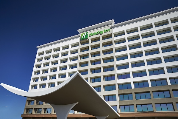 Edificio de un hotel Holiday Inn con diseño moderno, destacando un logotipo prominente en la fachada.