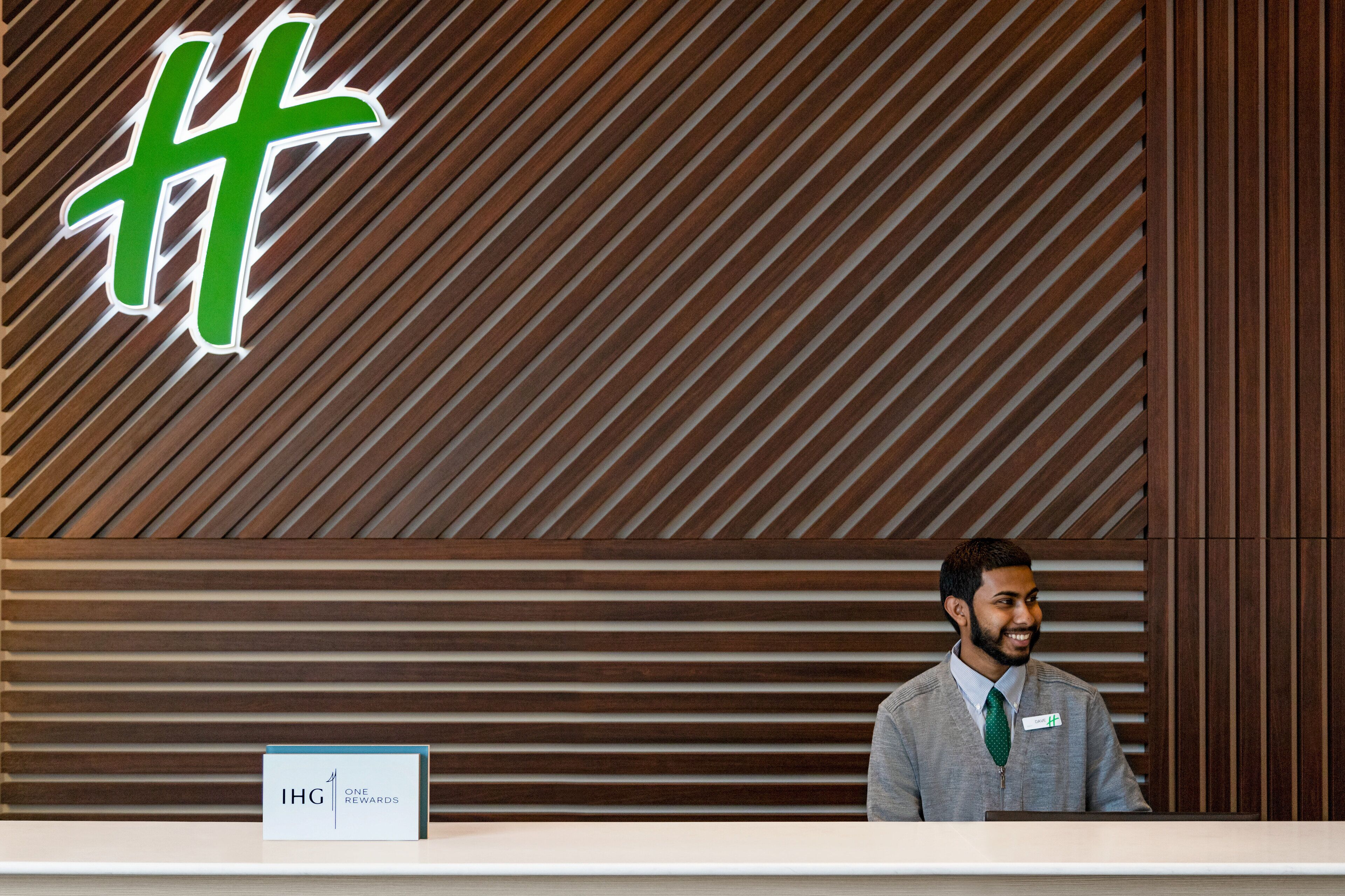 Un mostrador de recepción con un panel de listones de madera y un letrero que dice "IHG ONE REWARDS".