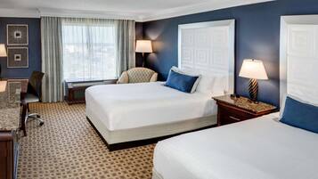 Une chambre d’hôtel avec deux lits, un bureau, une chaise, une machine à café et un téléviseur.