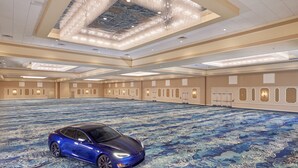A spacious hall with a blue carpet, a blue car, and a chandelier. - Rosen Plaza on International Drive (Orlando)