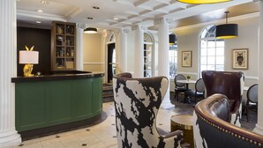 A lobby with a reception desk, a green counter, a bar area, and a seating area with leather chairs. - The Willows Hotel (Chicago)