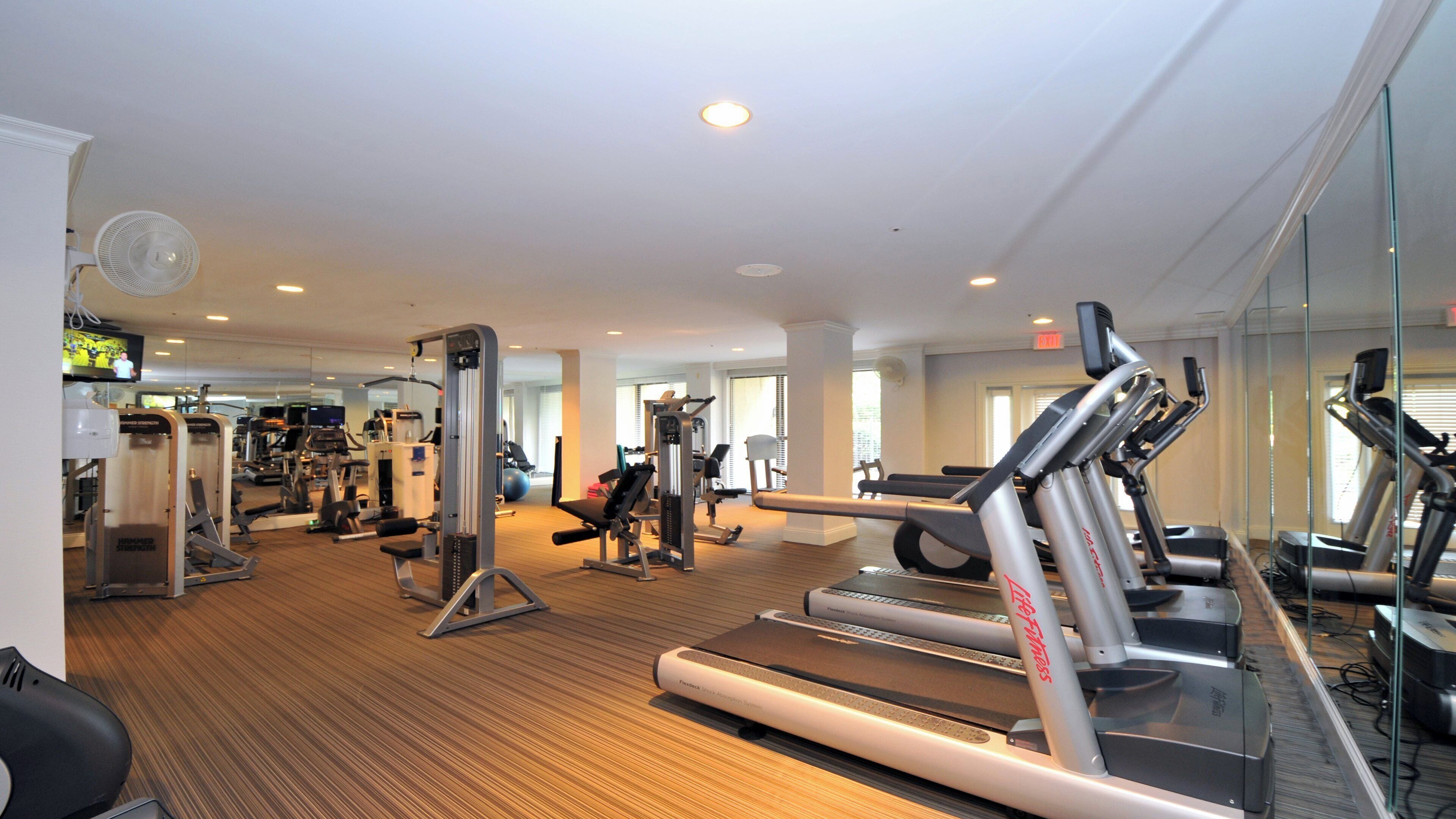 Un gimnasio con diversos equipos de ejercicio, incluyendo cintas de correr y máquinas de pesas.