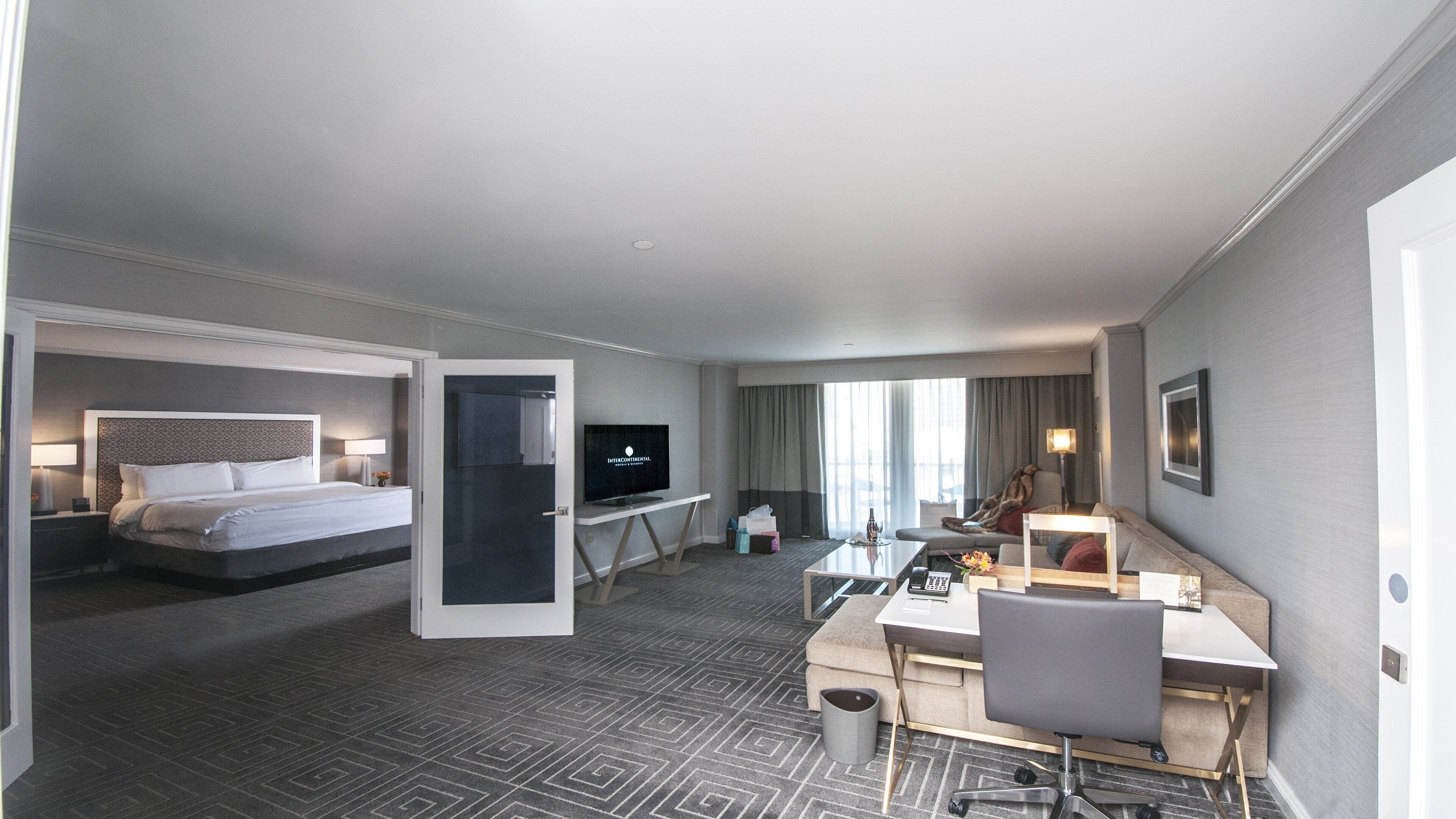 Une chambre d’hôtel avec un lit, un bureau, une télévision et un canapé.