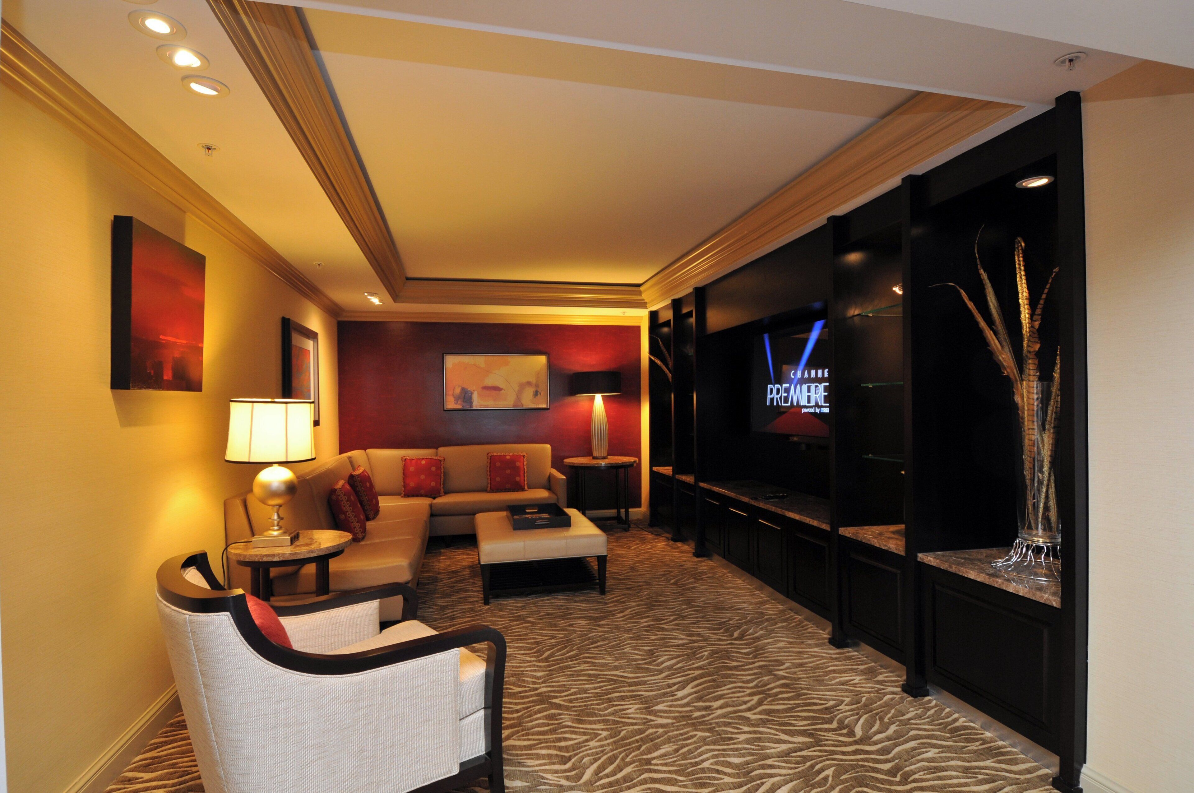 Una habitación de hotel con sofá, sillón y televisor de pantalla plana montado en la pared.