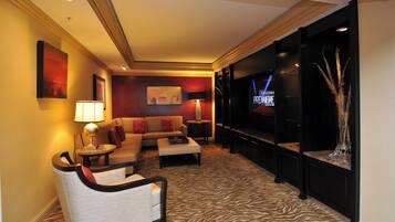 Una habitación de hotel con sofá, sillón y televisor de pantalla plana montado en la pared.