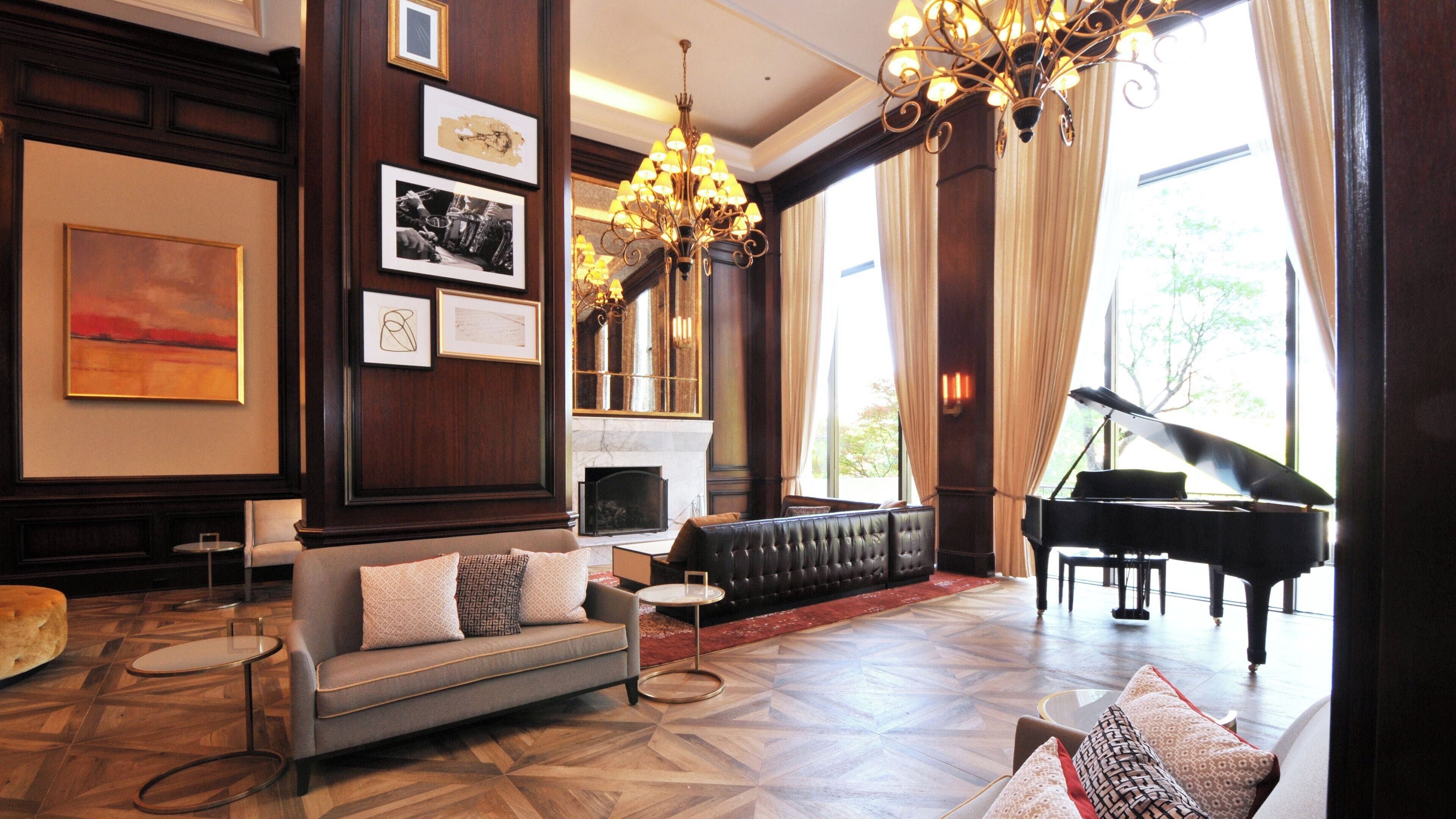 A spacious lounge with a grand piano, a fireplace, and a chandelier.