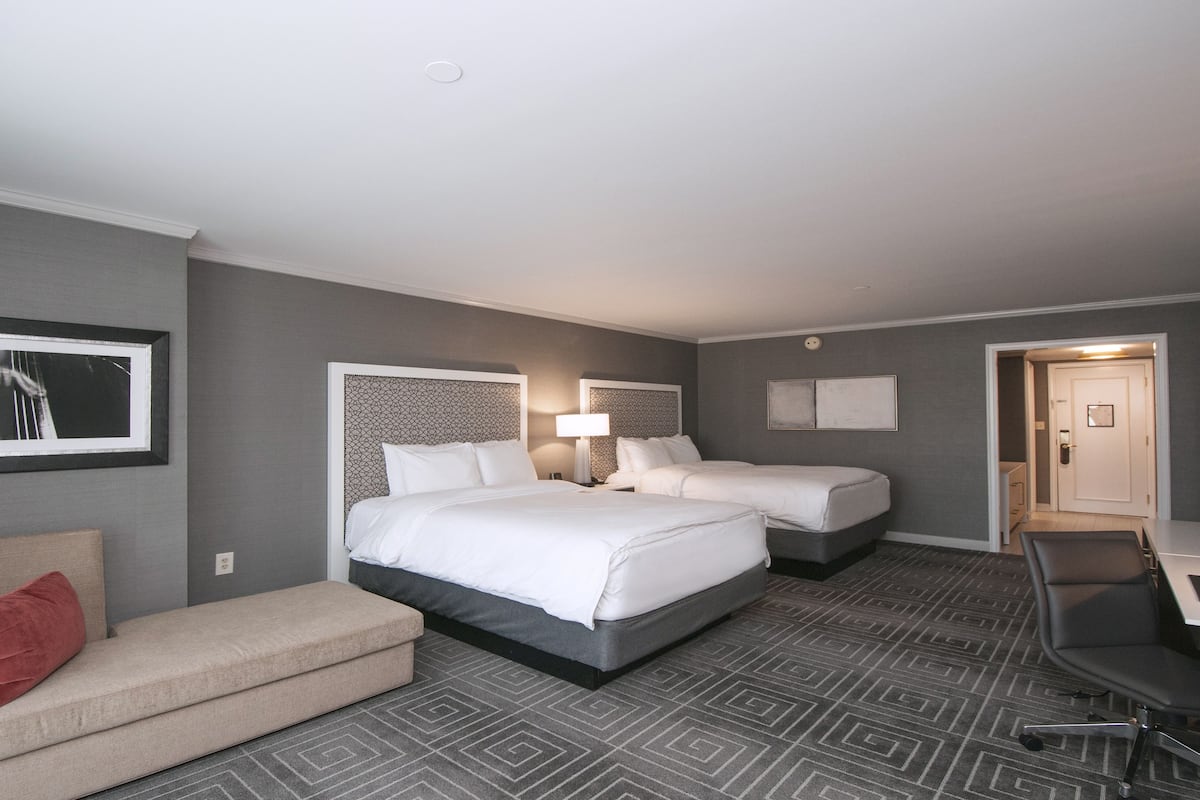 Habitación de hotel con dos camas, un sofá, un escritorio y una silla.