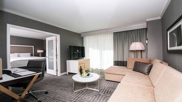Habitación de hotel con una cama, un sofá, un escritorio con una silla, un televisor y una lámpara.