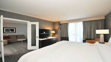 A hotel room with a large bed, a TV, a desk, and a sofa.