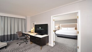 Una habitación de hotel con escritorio, silla, televisor y cama.