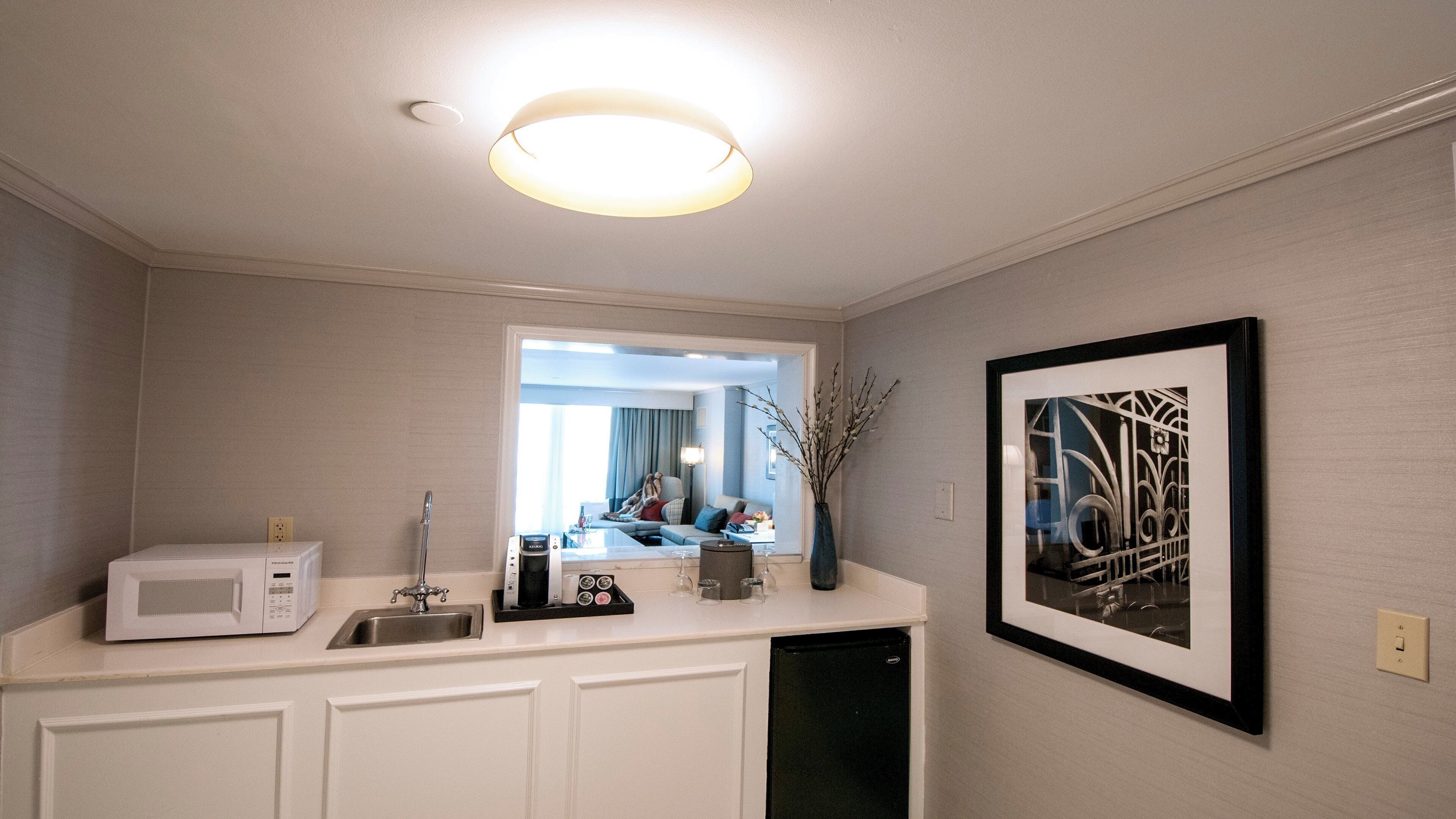 A bathroom with a white vanity, a sink, a mirror, a framed picture on the wall, and a ceiling light.