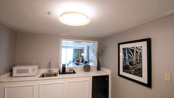 A bathroom with a white vanity, a sink, a mirror, a framed picture on the wall, and a ceiling light.