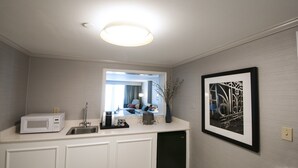 Un baño moderno con un lavamanos blanco, un microondas y una obra de arte abstracta enmarcada en la pared.
