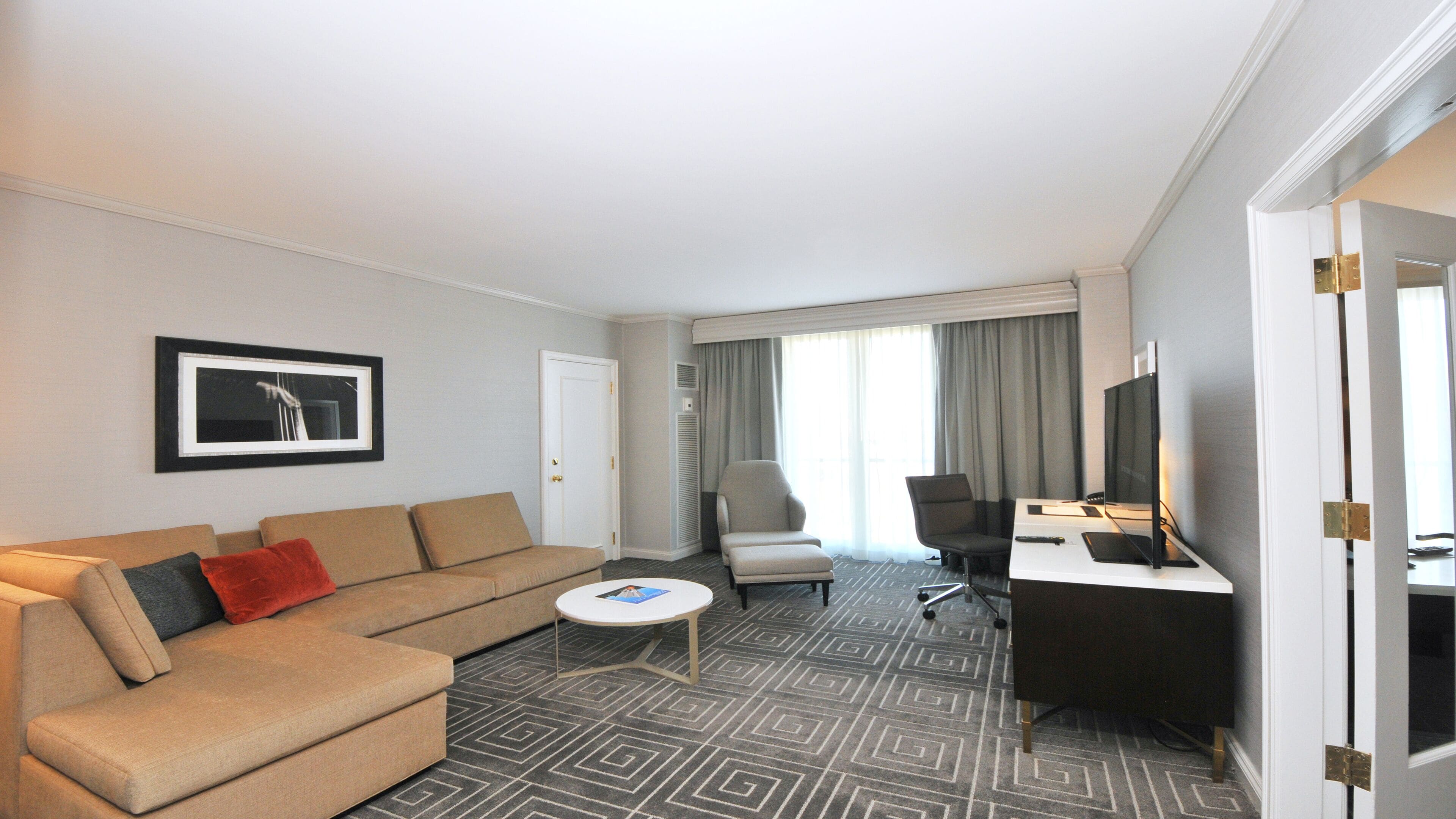 Une chambre d’hôtel équipée d’un canapé, d’un fauteuil, d’un bureau et d’une télévision.