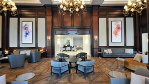 Een hotel lobby met een centraal zitgedeelte, banken en een eetruimte.