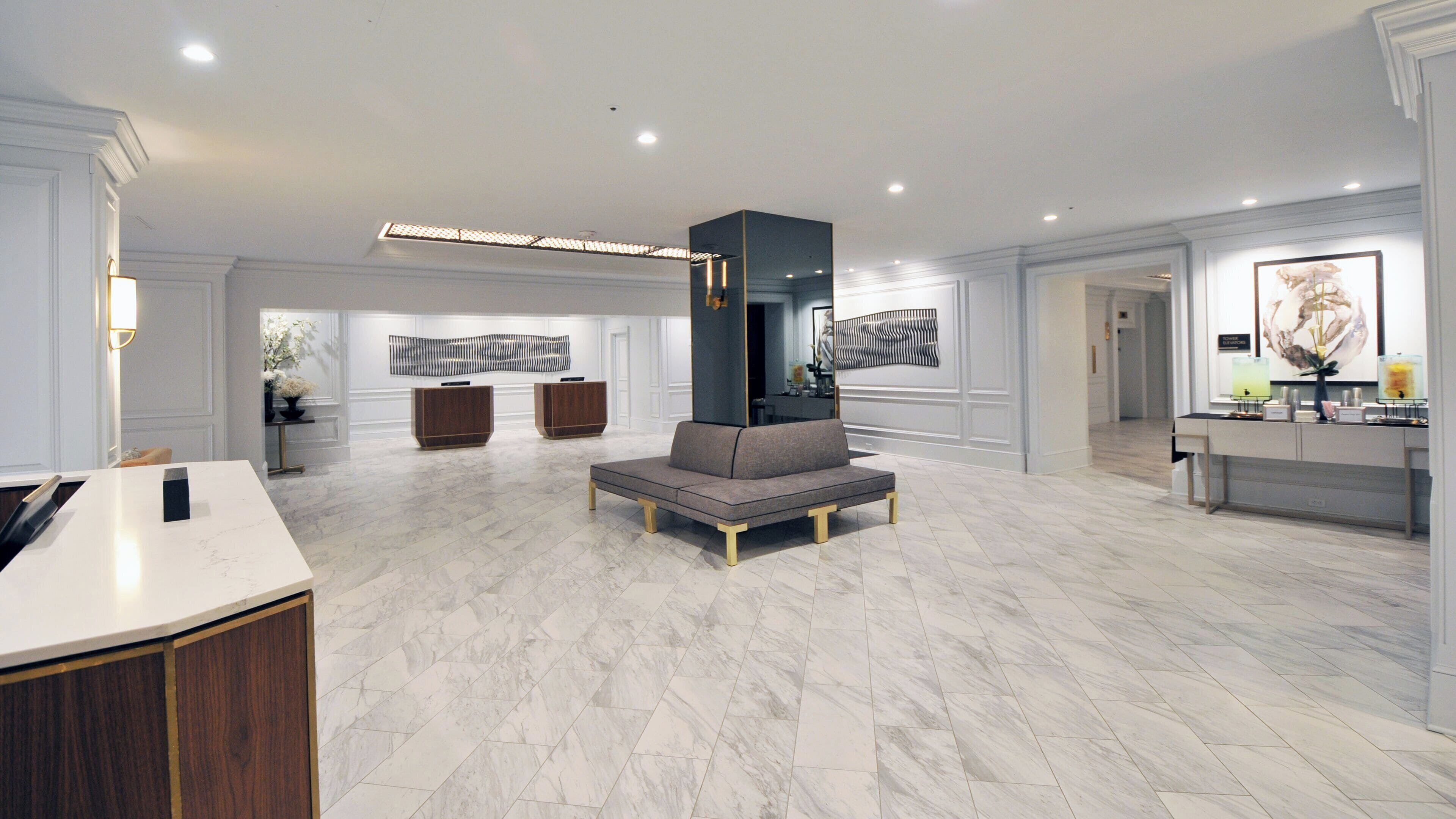 A spacious living area with a marble floor, a central seating area, and a reception desk.