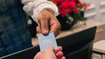 A person holding a card with "IHG REWARDS" printed on it.