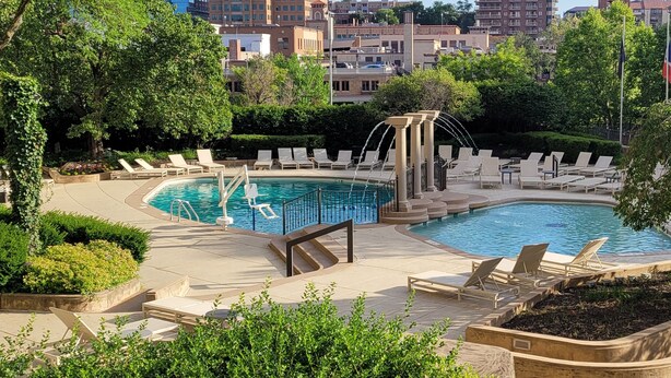 Un área de piscina con sillones reclinables y una fuente.