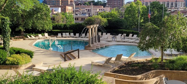 Un área de piscina con sillones reclinables y una fuente.