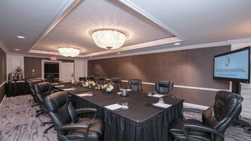 A conference room with a long table, leather chairs, a chandelier, and a screen displaying the Intercontinental Hotels & Resorts logo.