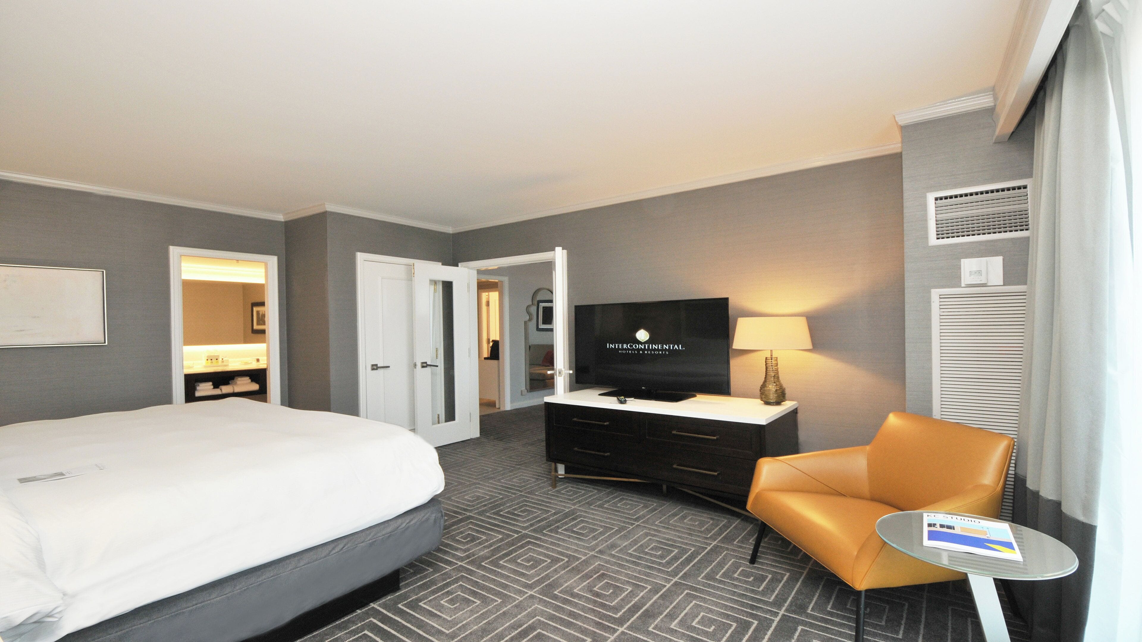 A hotel room with a bed, a TV, a desk, a chair, and a small table.