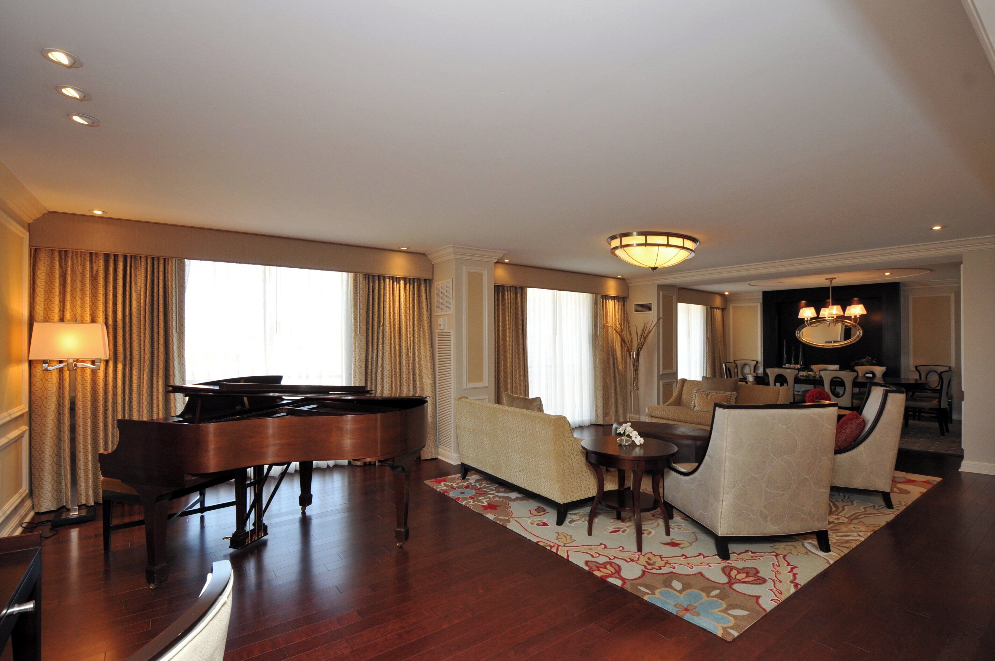 Un salón comedor amplio con un piano de cola, un conjunto de sofás y una zona de estar.