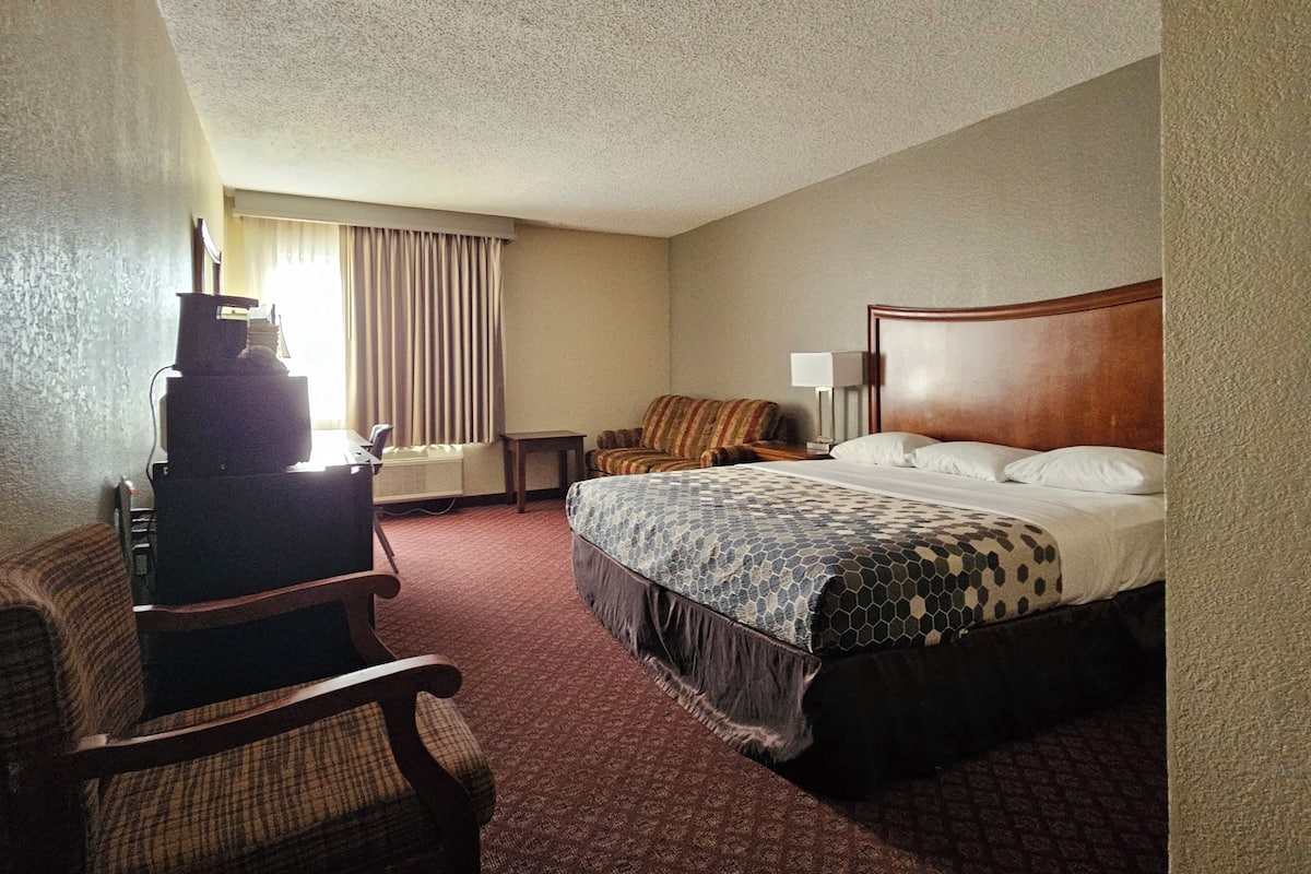 A hotel room with a bed, a chair, a desk, and a television.