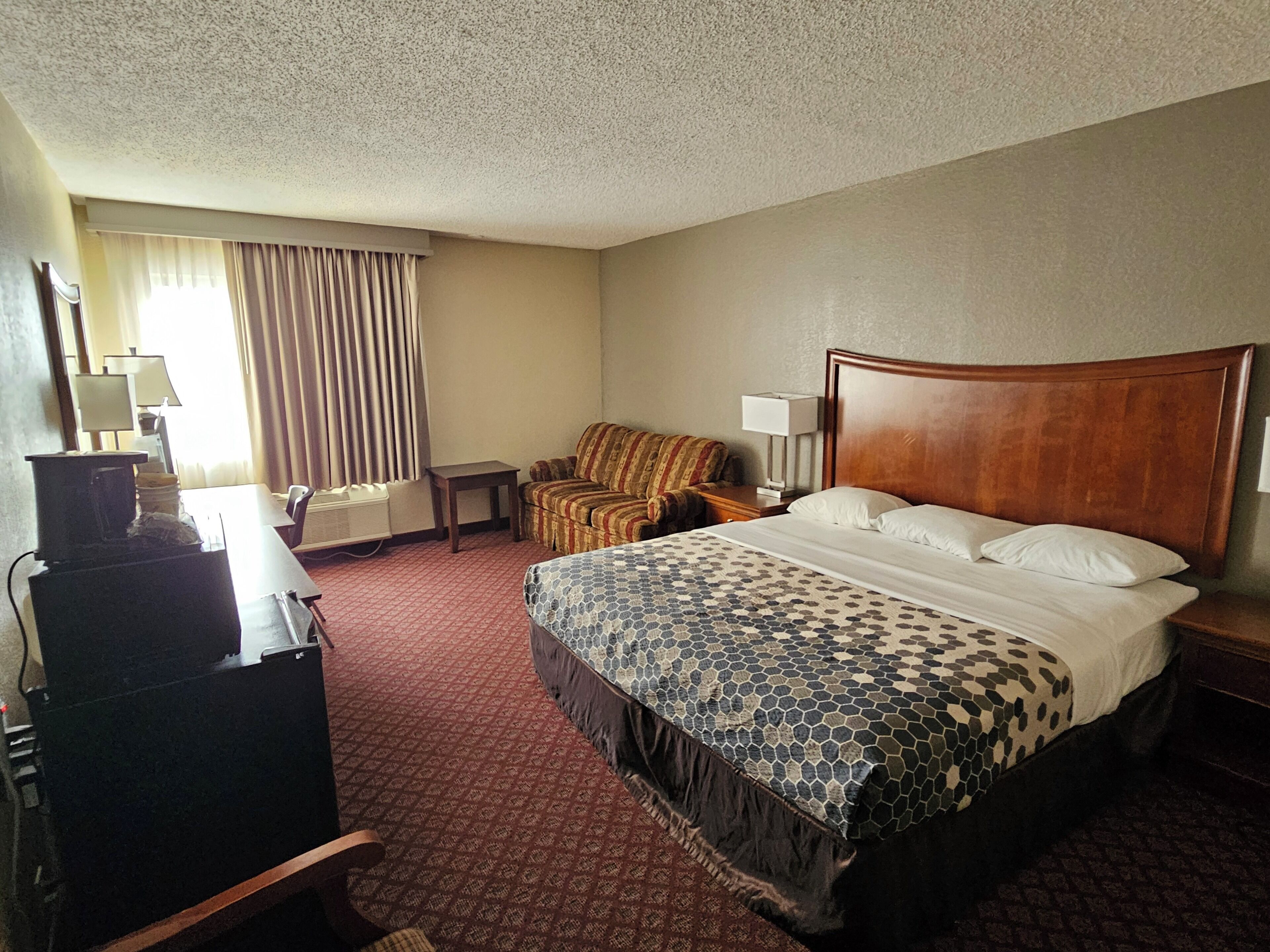 Une chambre d’hôtel avec un grand lit, un canapé, un bureau avec une lampe et un téléviseur.