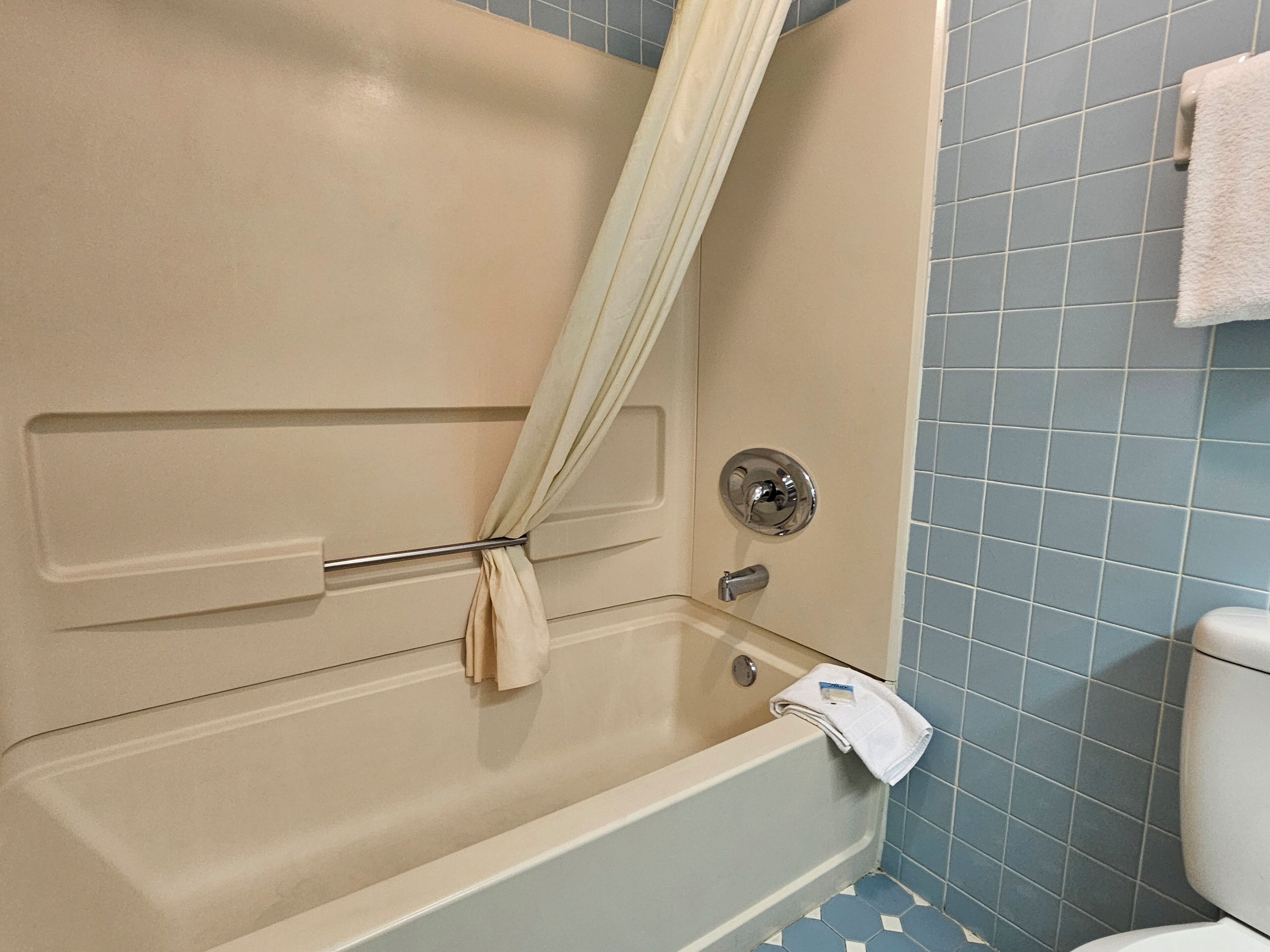 A bathroom with a bathtub, a toilet, and a towel rack.