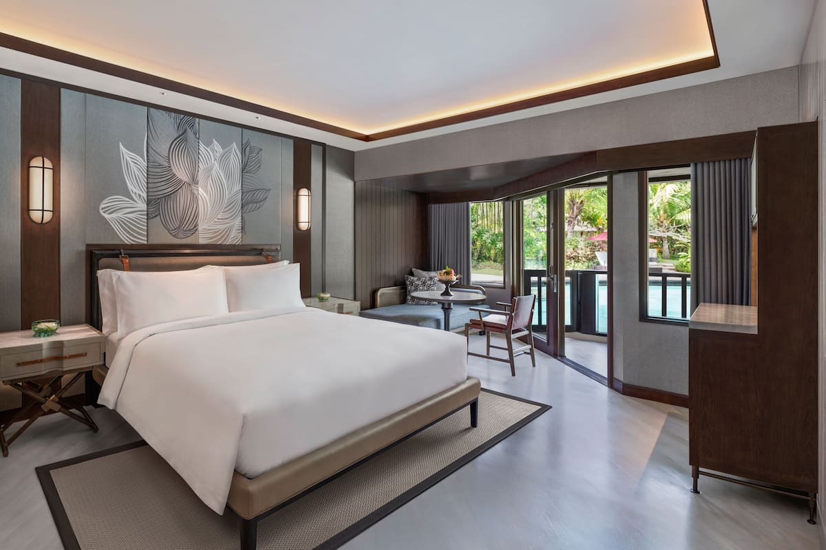 A modern hotel room with a large bed, a small table, and a balcony with a view.