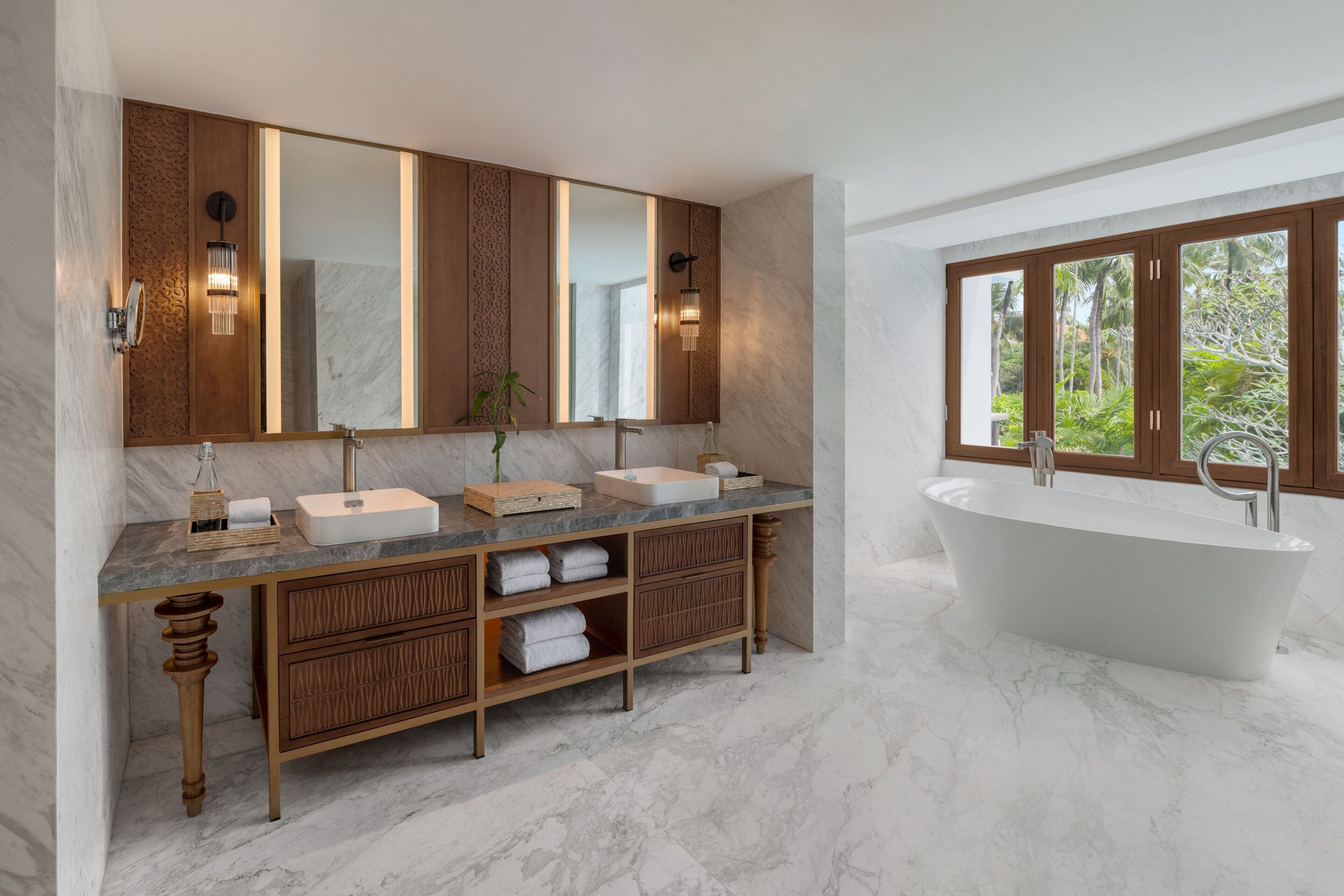 Un baño moderno con una bañera independiente, un tocador amplio con dos lavamanos y un espejo grande.