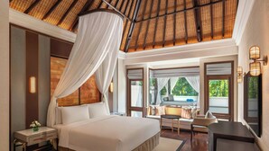 A spacious bedroom with a large bed, a canopy, and a view of greenery outside.