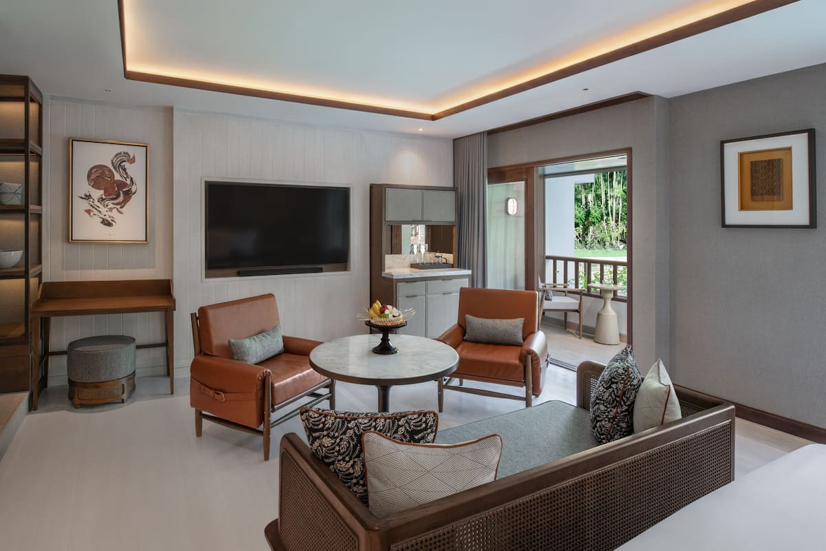 A modern living room with a sofa, chairs, a round coffee table, a flat-screen TV, and a dining area with a table and chairs.