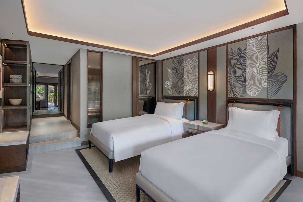 A hotel room with two beds, a large decorative wall, and a view of the outdoors.