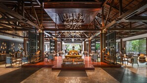 A spacious lobby with a high ceiling, wooden beams, and a central seating area with a chandelier.