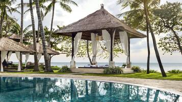 Relax by the serene pool surrounded by lush greenery and ocean views.
