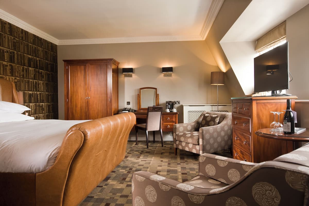 Een hotelkamer met een groot bed, een bureau, een stoel, een kledingkast en een televisie.
