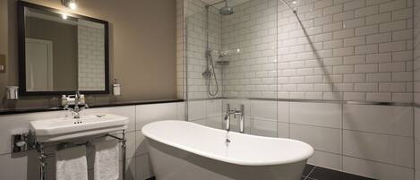 A modern bathroom with a freestanding bathtub, a sink with a mirror above it, and a shower area.