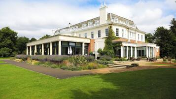 Stately building with a classical facade, surrounded by well-manicured lawns and lush gardens.