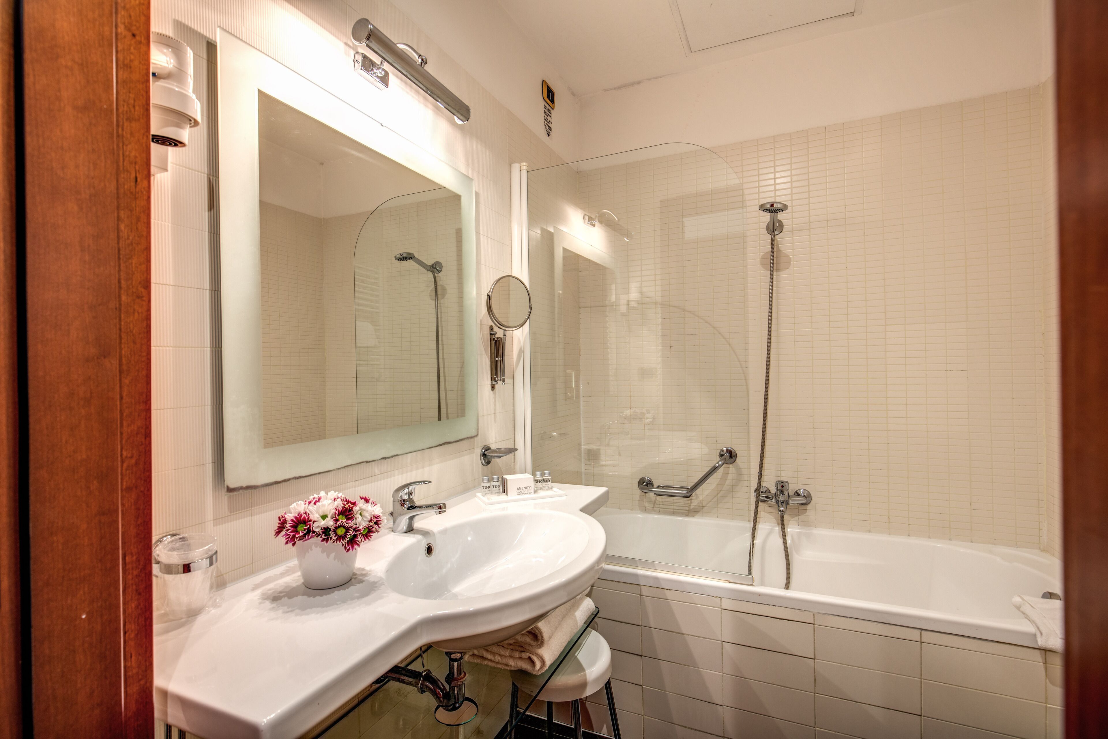 Un baño moderno con lavamanos, espejo y bañera blancos.